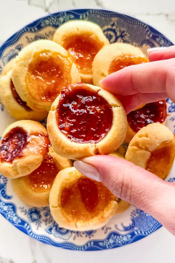 Close up of buttery thumbprint cookie showing jam-filled center.
