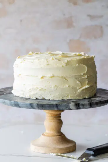 Simply frosted vanilla cake on cake stand.