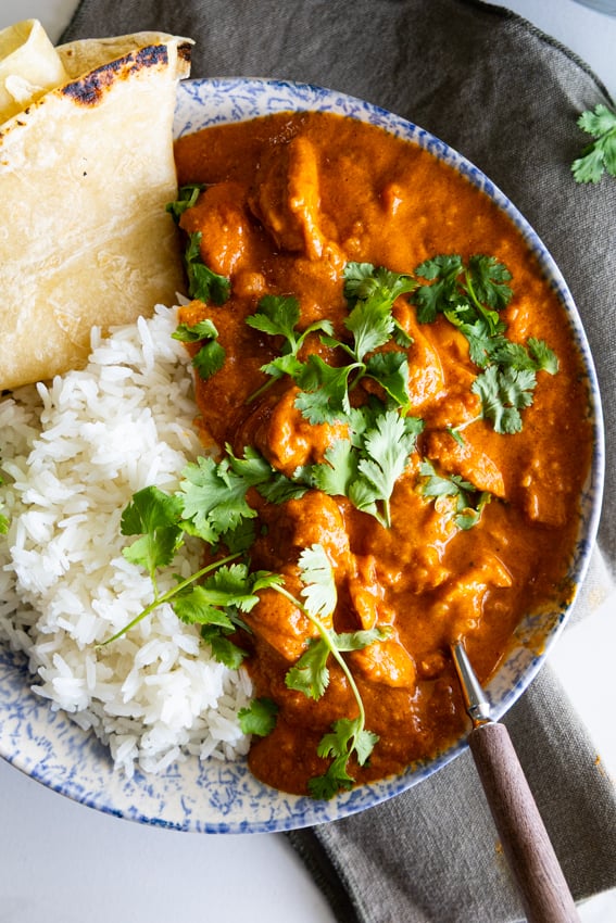 Butter Chicken curry with rice and roti garnished with fresh cilantro.