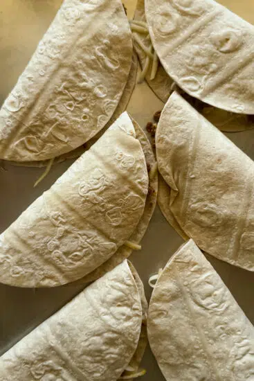 Filled tortillas on baking sheet.