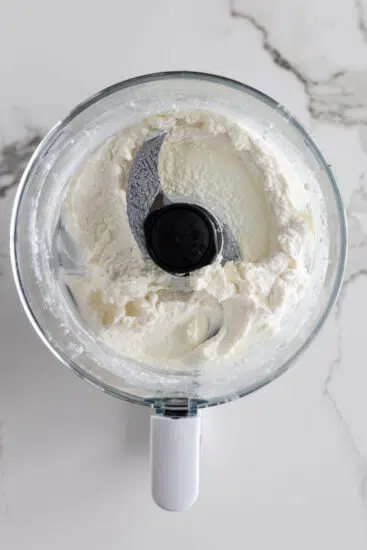 Blended cottage cheese in food processor bowl.