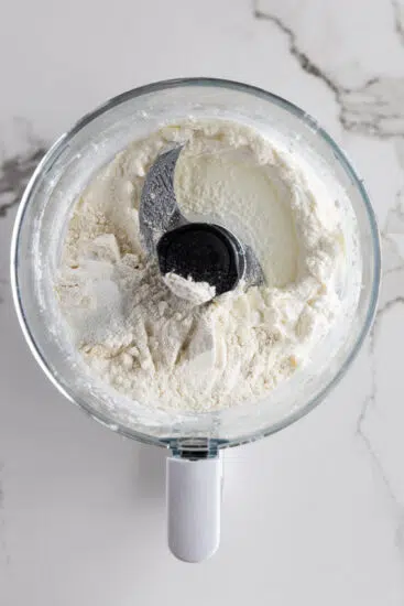 Cottage cheese, flour and baking powder in the bowl of a food processor.