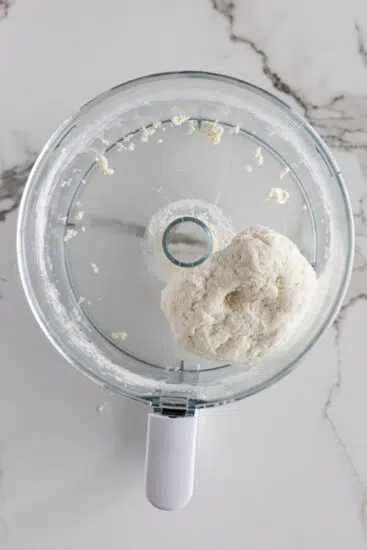 Cottage cheese tortilla dough in the bowl of a food processor.