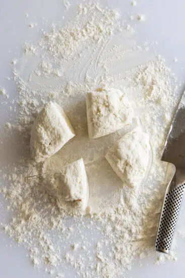 Cottage cheese tortilla dough cut into 4 portions on floured surface.