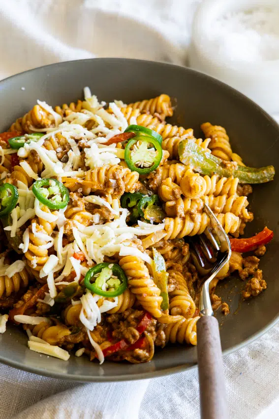 Taco pasta in a serving bowl topped with cheese.