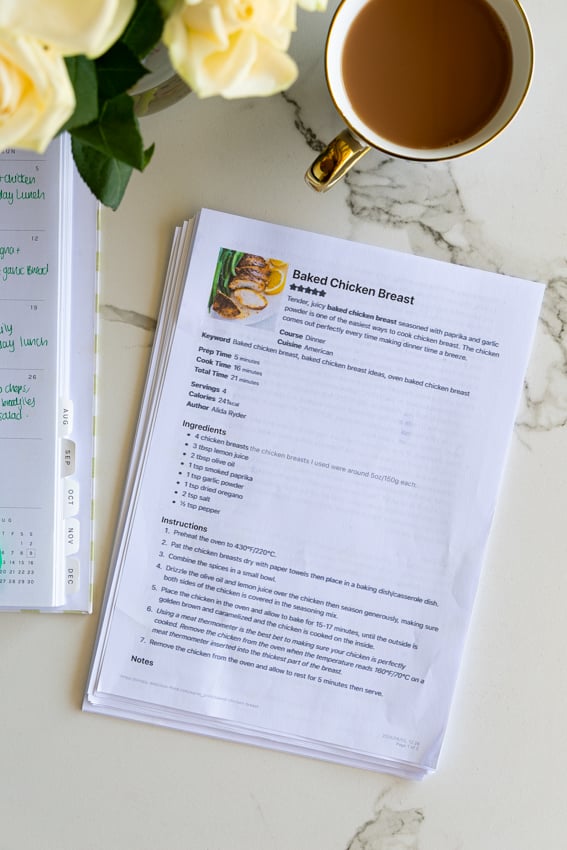 Printed recipes on kitchen counter with cup of tea and roses.