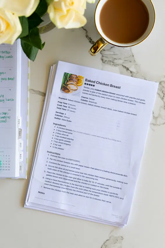 Printed recipes on kitchen counter with cup of tea and roses.