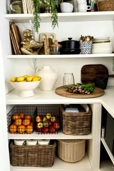 Pantry with baskets of fresh fruit, paper towels and general kitchen wares.