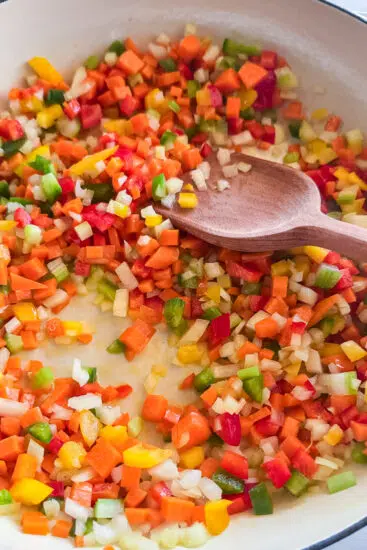 Vegetables frying in large pan.