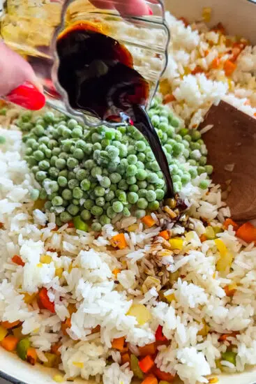 Frozen peas and soy sauce added to pan with rice and vegetables.