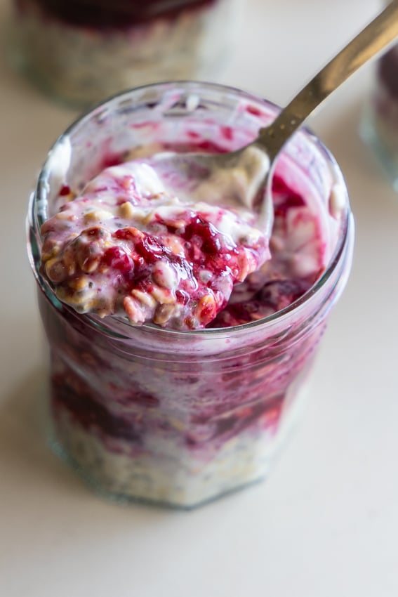 Creamy overnight oats with chia seeds, layered with berry sauce in jars.