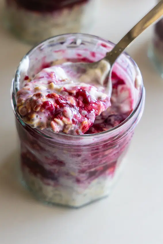 Creamy overnight oats with chia seeds, layered with berry sauce in jars.