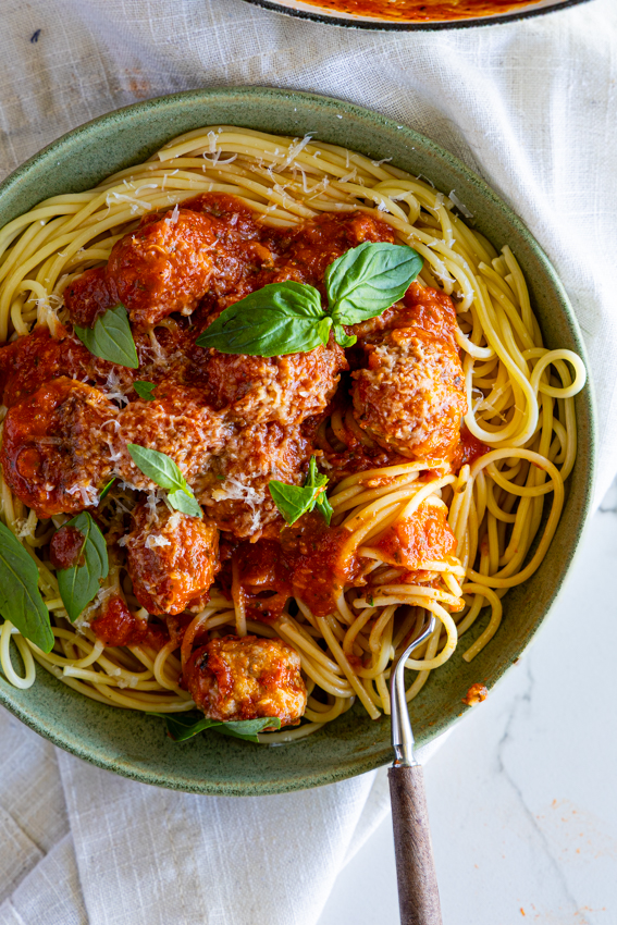 Pork Sausage Meatballs with Spaghetti in green serving bowl.