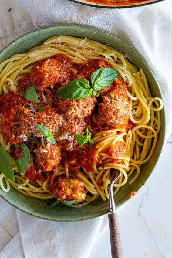Pork Sausage Meatballs with Spaghetti in green serving bowl.