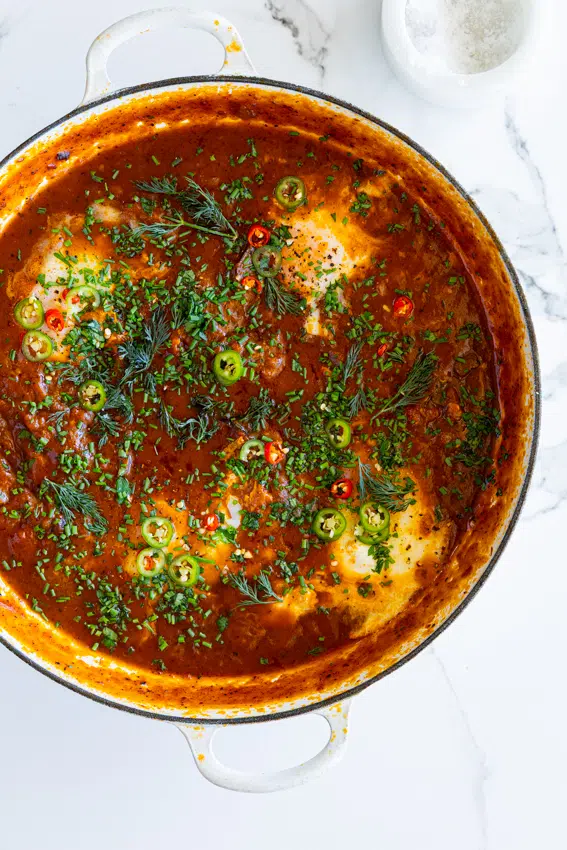 Easy Shakshuka in a pan with fresh herbs.
