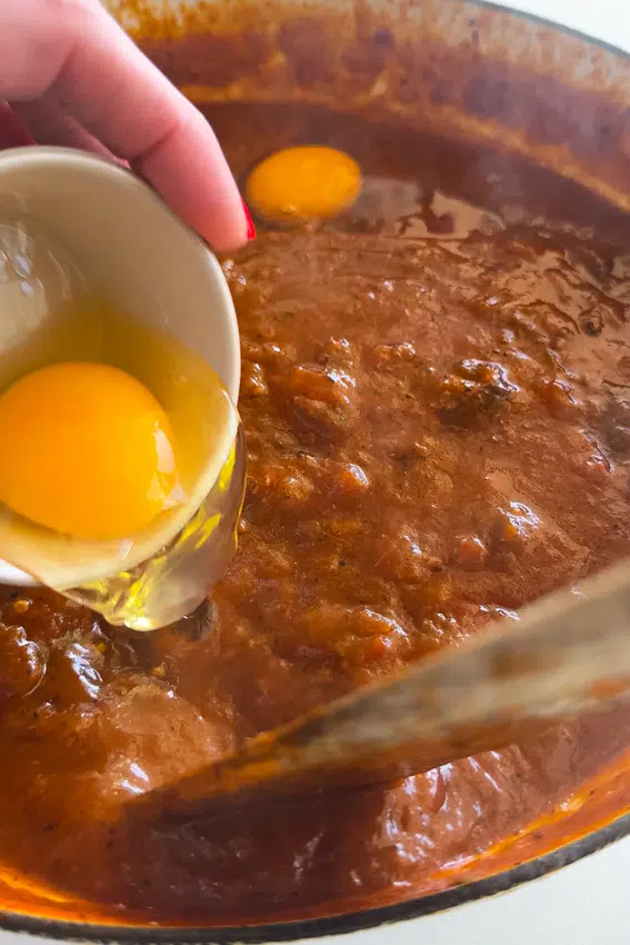 Eggs dropped in simmering tomato sauce for Shakshuka.