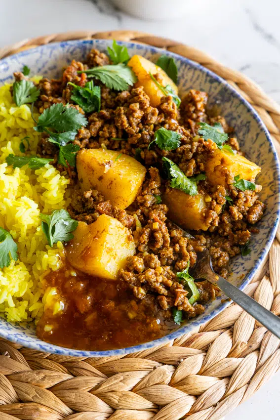 Ground beef curry with potatoes served with turmeric rice and chutney.
