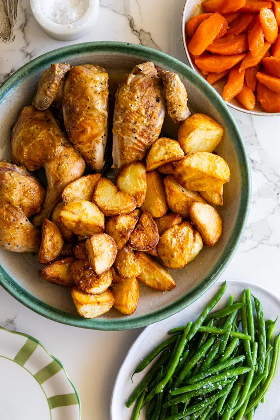 Roast chicken dinner with roasted potatoes, green beans and glazed carrots.