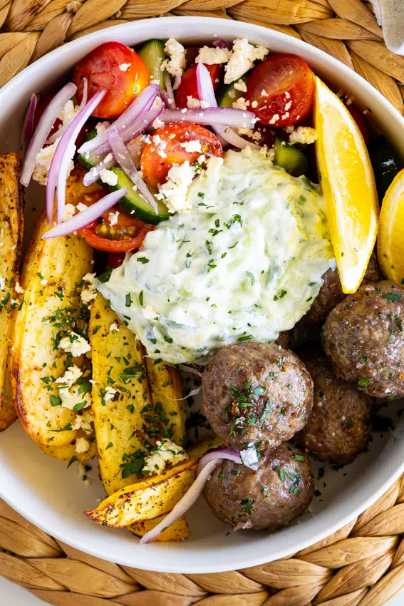 Greek meatball bowls with lemon potatoes, cucumber tomato salad and tzatziki.