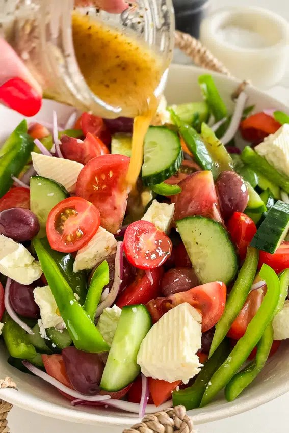 Homemade Greek salad dressing poured over Horiatiki salad.